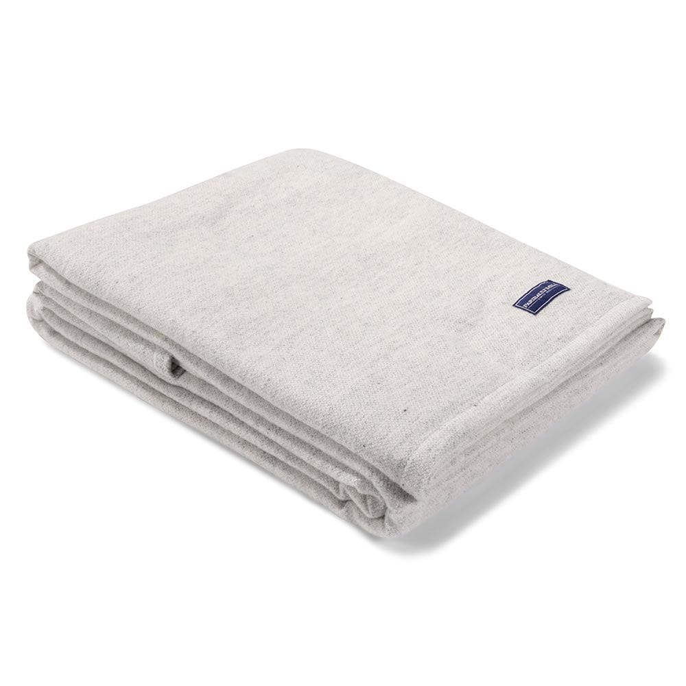 Faribault Mill Lakefront natural lightweight wool bed blanket, folded and displayed at an angle to highlight the thickness, loft of the wool, and whipstitched edges.