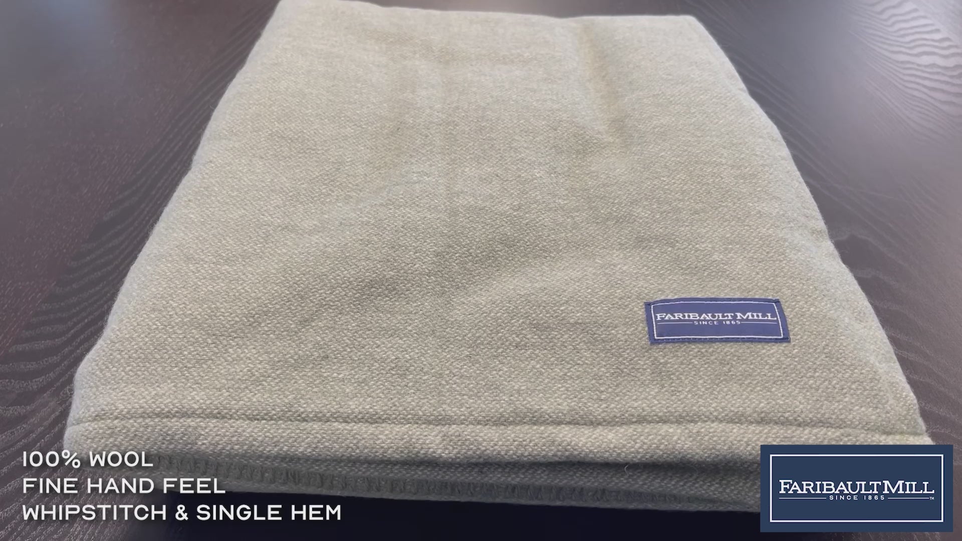 Close-up video of a hand feeling the soft, lofted texture and whipstitched edge of the natural Lakefront wool blanket.