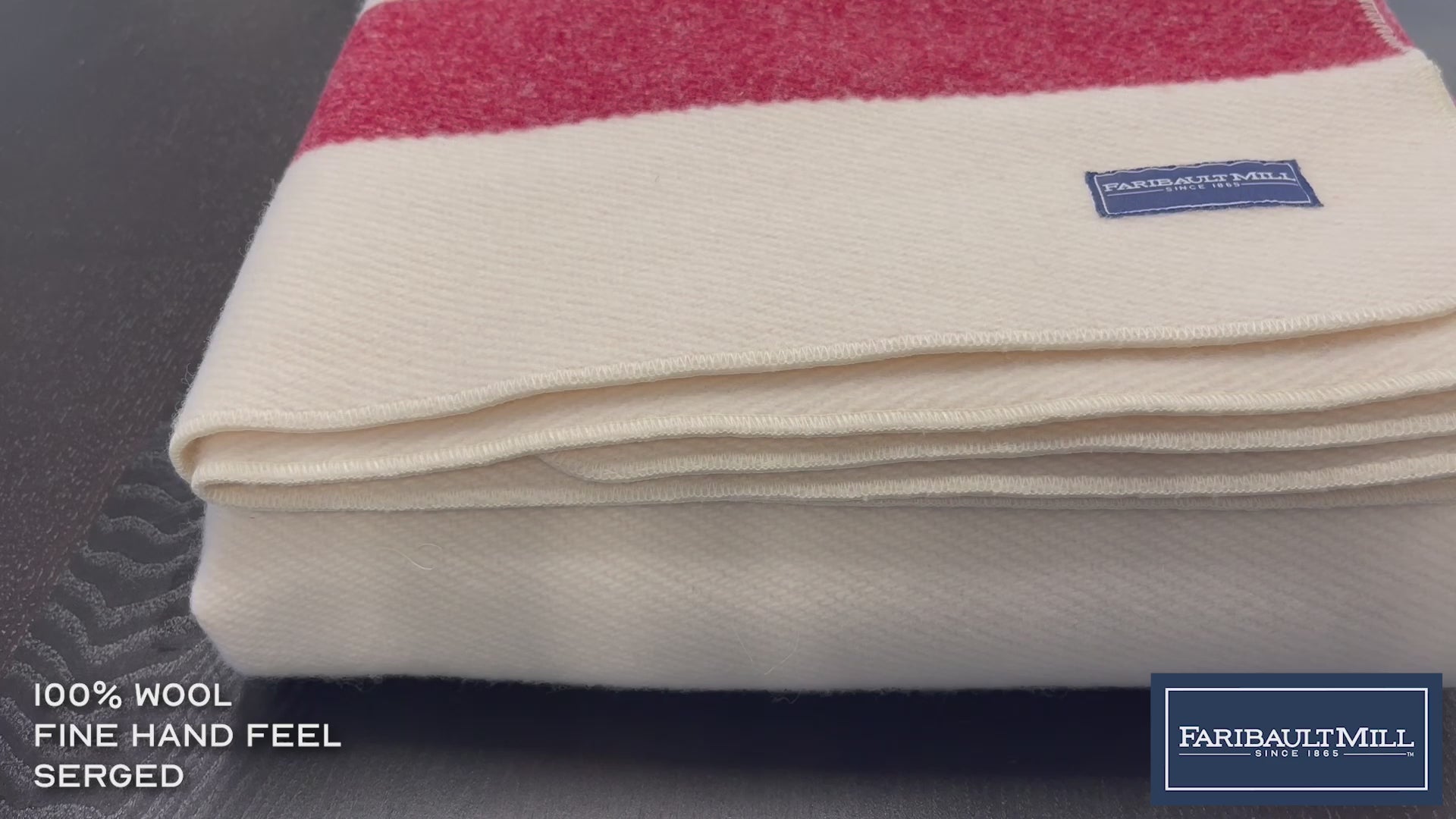 Close-up video of a hand feeling the soft, lofted texture and whipstitched edge of the natural Frontier wool blanket.